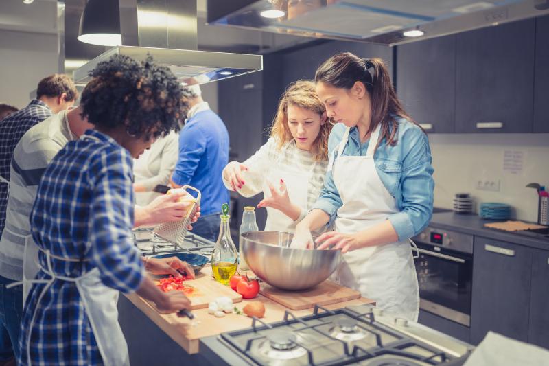 Group of people cooking a veggie meal together
