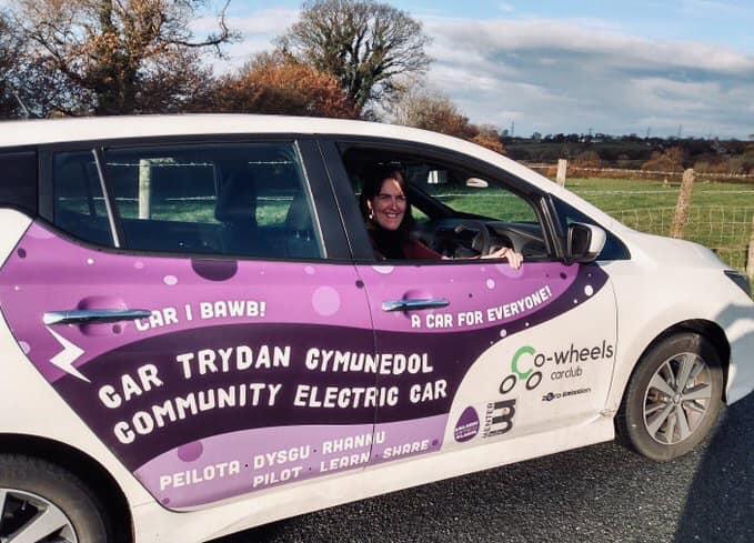 Meleri Davies in driving seat of Carwen, the electric car, Welsh landscape in the background