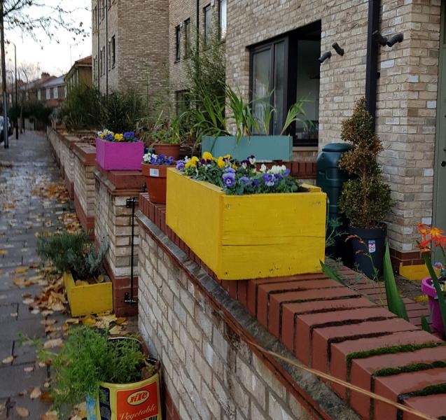 Homemade yellow wooden planter on front garden wall