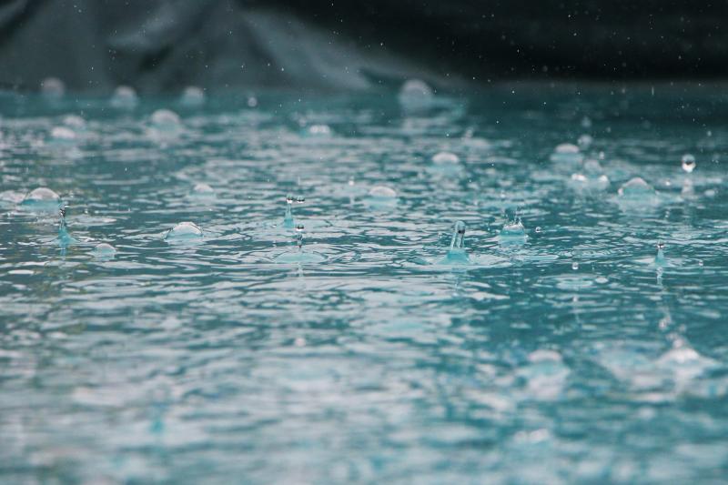 Close up of rain drops causing ripples on surface of water
