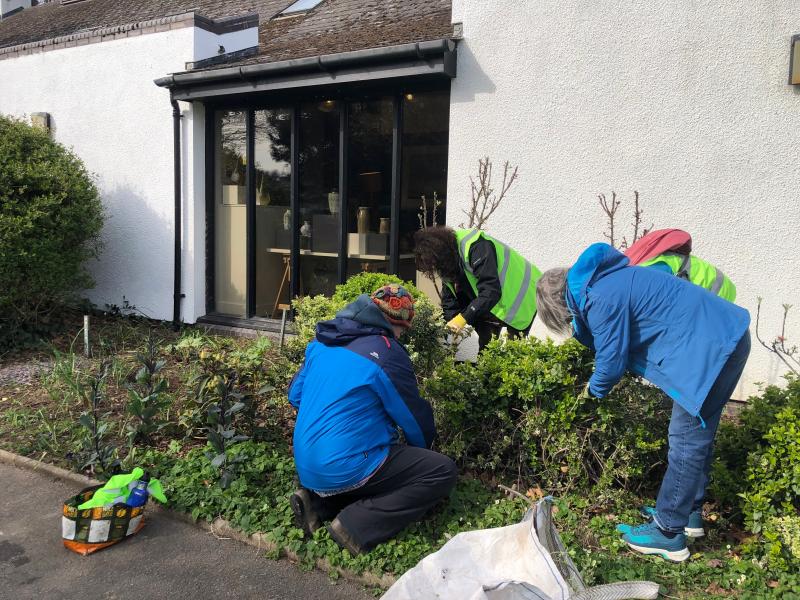 3 Volunteers working in flowerbed outside white building in 10xG community greening project Bideford