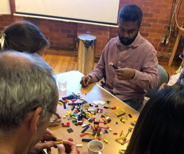 4 people around a table in a workshop using lego as a design tool
