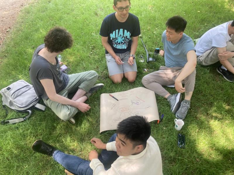 Group of students sitting on grass discussing notes on a flip chart