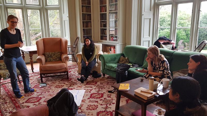 4 women workshop participants sitting in country house library listen to female presenter