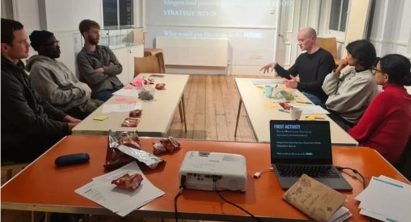 6 people in a meeting in conversation around a table, boardroom-style