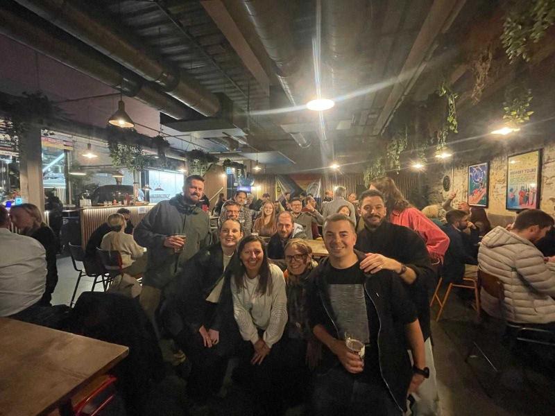 Group of people in pub laughing and waving at camera