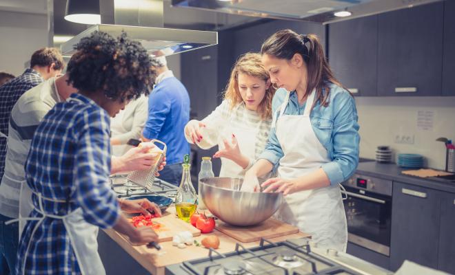 Group of people cooking a veggie meal together
