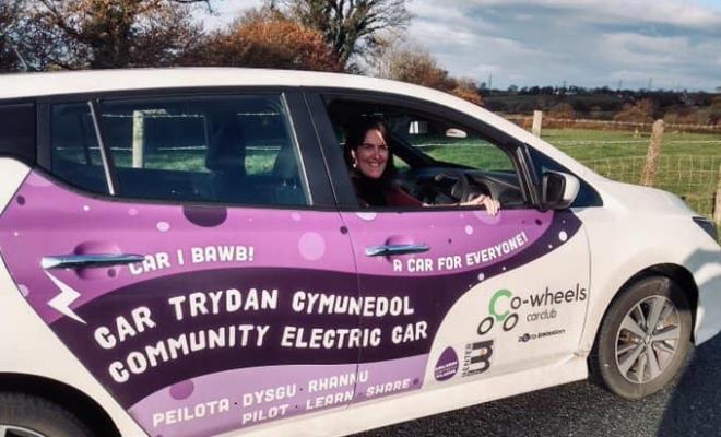 Meleri Davies in driving seat of Carwen, the electric car, Welsh landscape in the background
