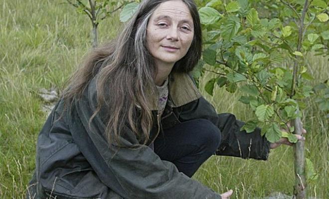 Dongria kneeling by tree sapling and looking up at camera