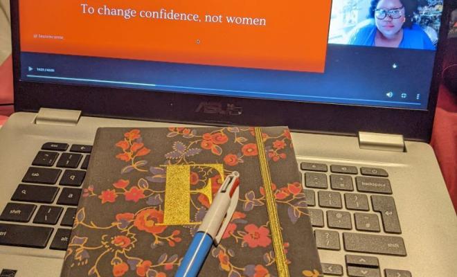 UPFRONT logo on computer screen, notebook and pencil on desk in foreground
