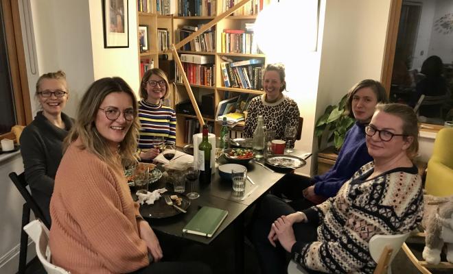 A group of women sitting round a table and smiling to camera