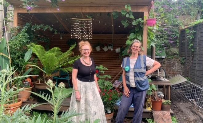 Postcode Gardener standing in front of summer house in garden with garden owner